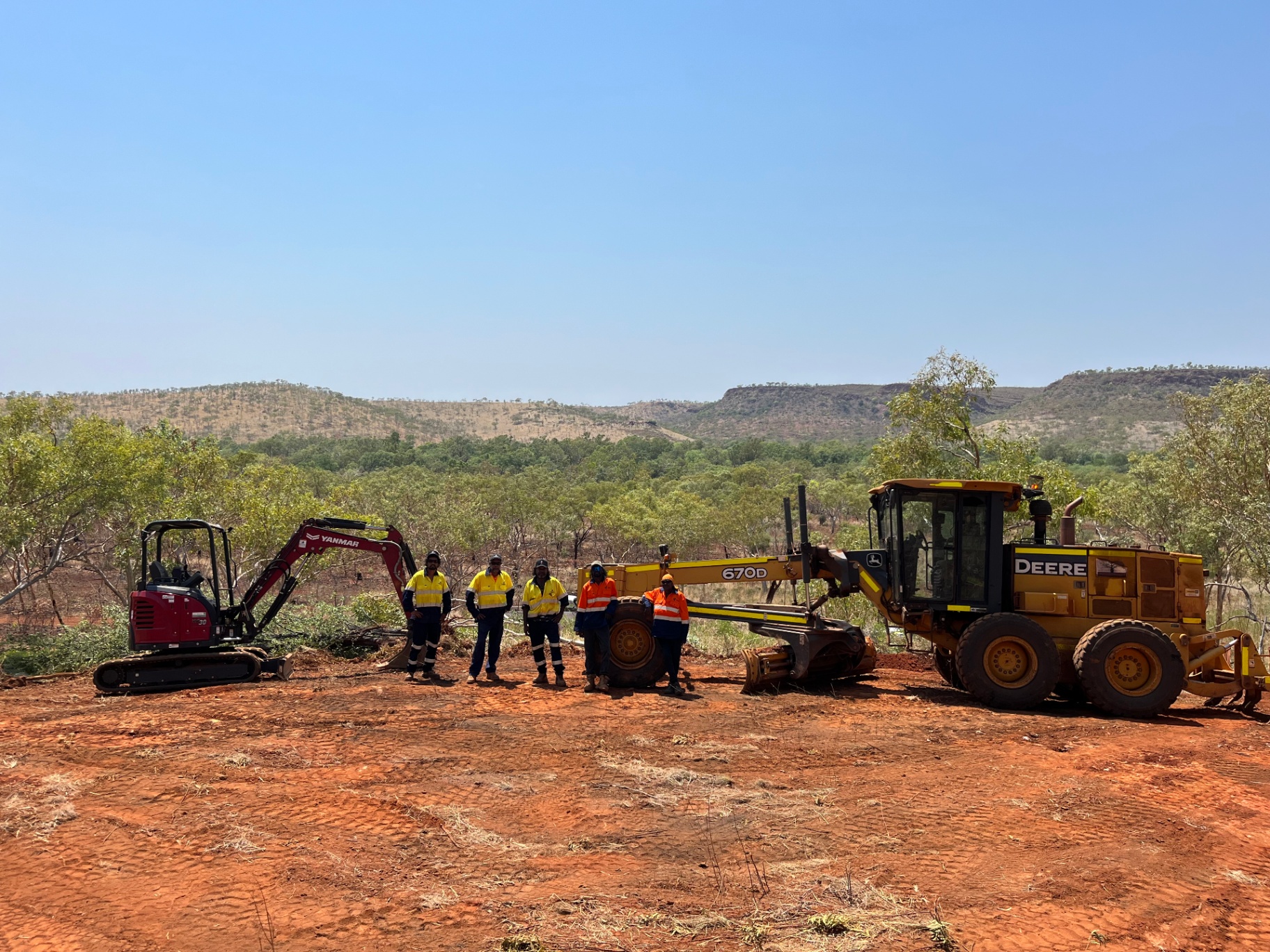 Aboriginal civil crew on country in the East Kimberley with grader and excavator, ranges in the distance